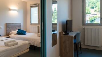 A hotel room with two beds, a desk with a computer, and a view of a residential area.