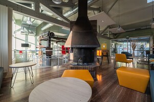 Un interior moderno con una chimenea grande, zonas de estar y ventanas amplias.