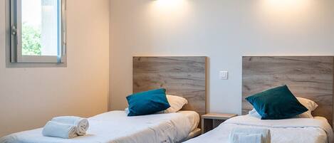 Una habitación de hotel con dos camas, una ventana e iluminación instalada en la pared.