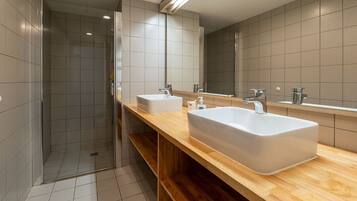 Un bagno moderno con doccia, due lavandini e un grande specchio.