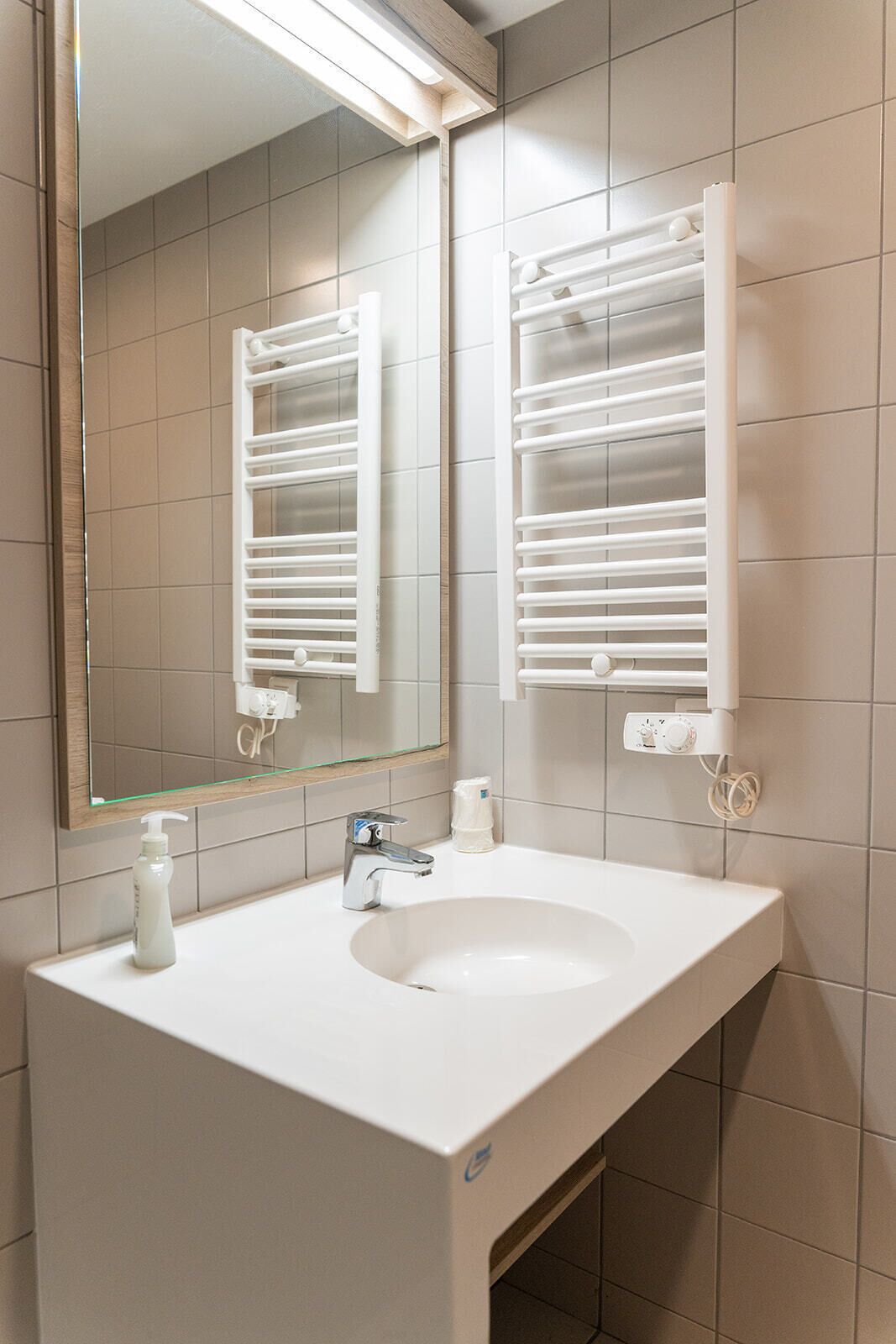 A bathroom with a white sink, a mirror, and towel racks.
