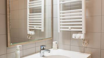 A bathroom with a white sink, a mirror, and towel racks.