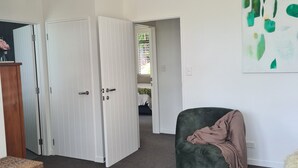A room with a green chair, a white door, and a painting on the wall.