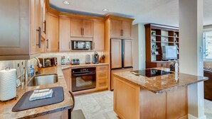 A kitchen with wooden cabinets, a microwave, oven, refrigerator, and a built-in island with a sink. - Sun Vail 21b, 3BD Condo With Vail Mountain Views (Vail)