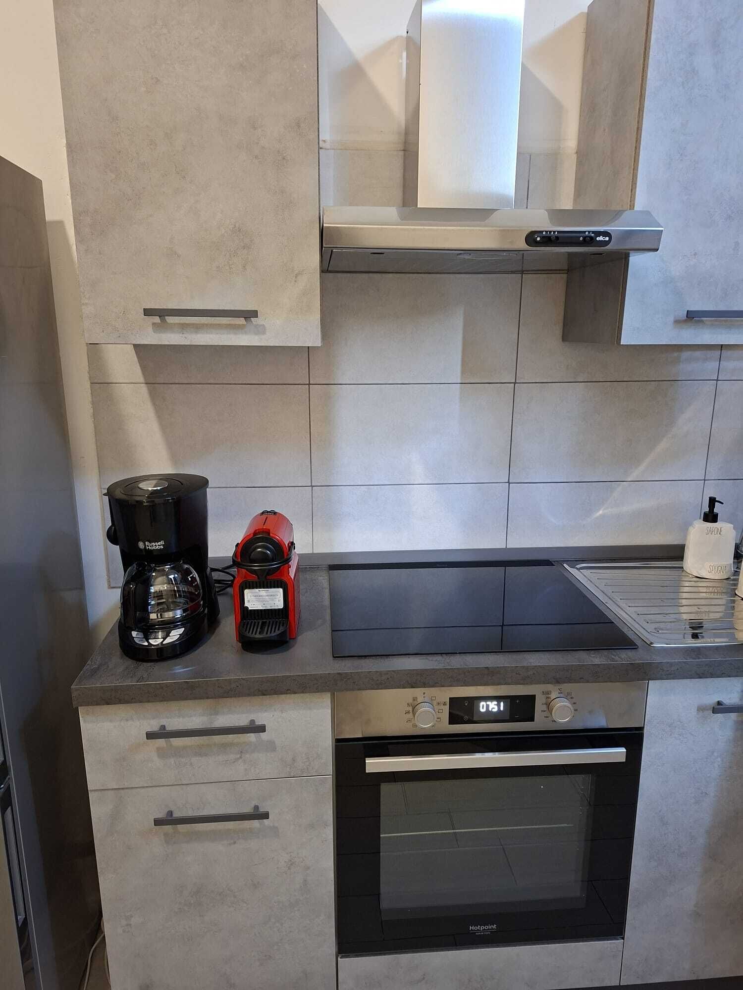 A modern kitchen with a built-in oven, a coffee maker, and a red appliance on the countertop.