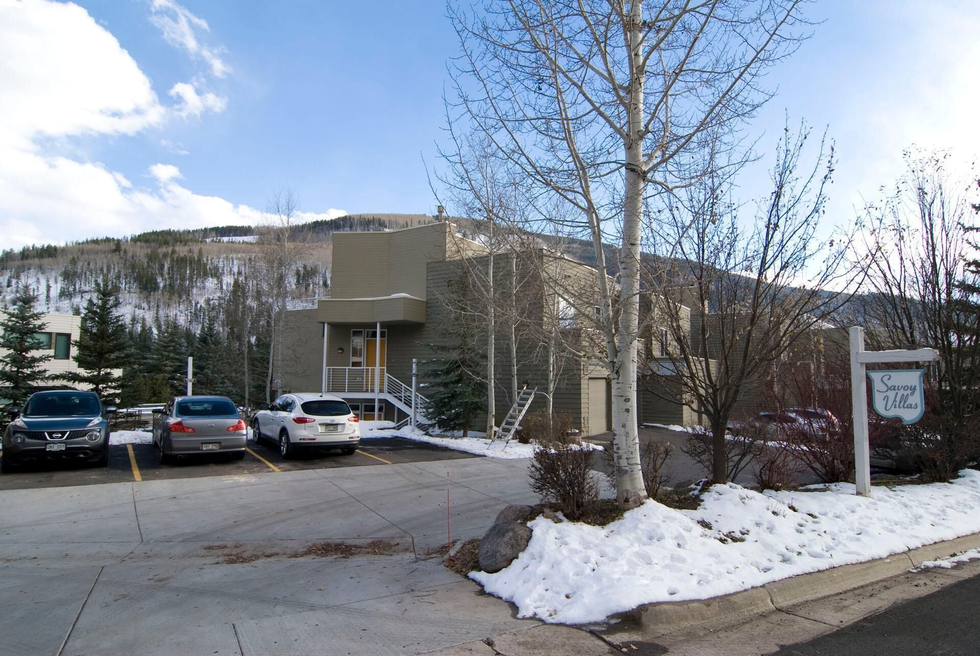 A building with a parking lot, a sign for 'Savoy Villas,' and a snow-covered landscape.