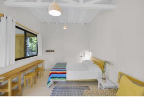 A bedroom with a bed, a bench, a table, a window, and a hanging light fixture. - Perfect studio with AC in sunny Santa Teresa (Santa Teresa)
