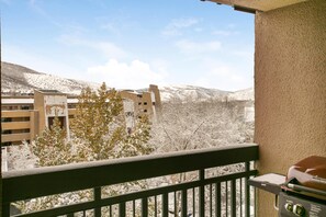 Ein Balkon mit Grill, der auf eine verschneite Landschaft mit Gebäuden und Bäumen blickt.