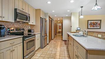 Una cocina equipada con microondas, estufa, refrigerador y lavaplatos.