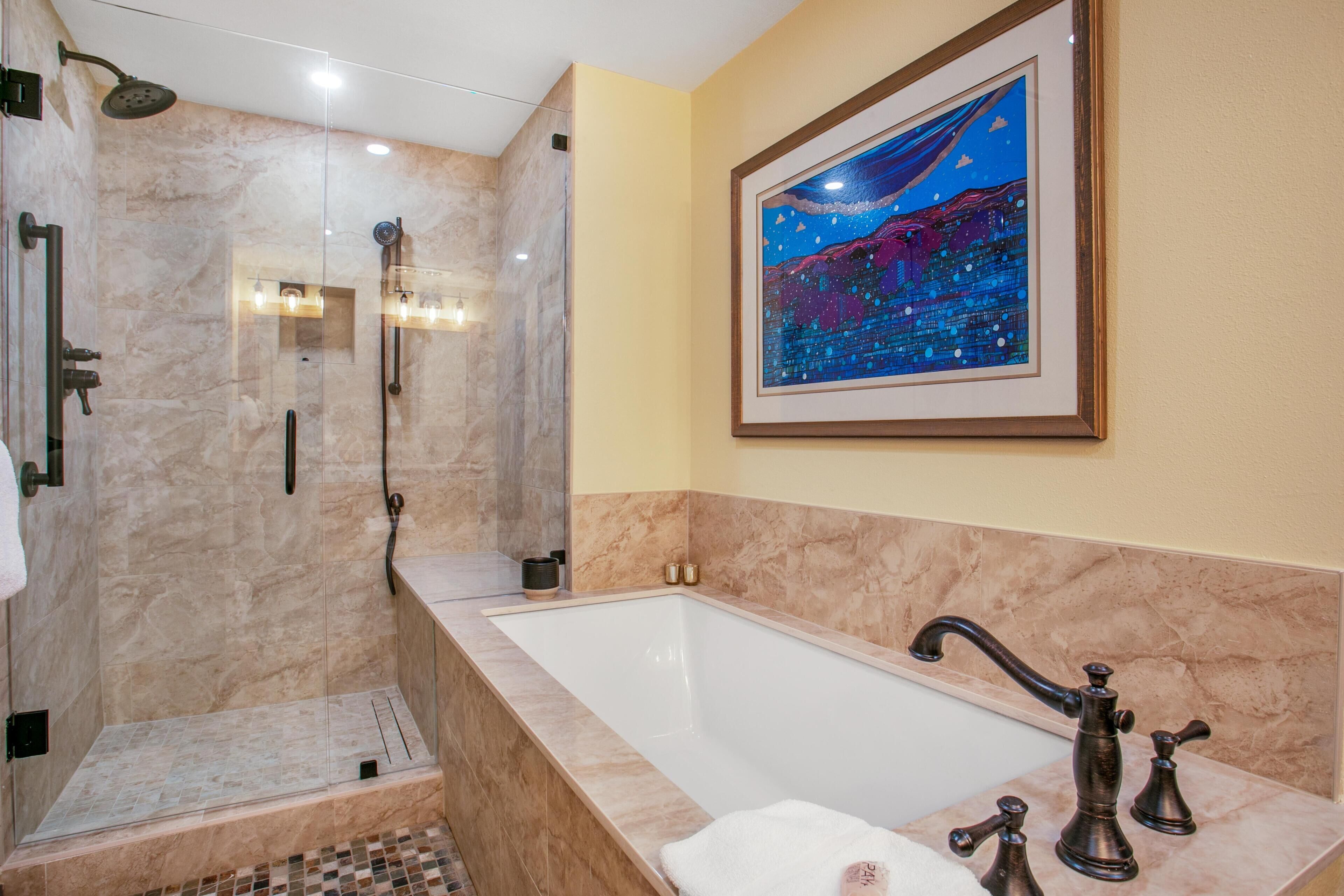 Une salle de bain dotée d’une douche à parois de verre, d’une baignoire sur pieds et d’une œuvre d’art encadrée au mur.