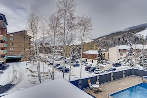 Zona residenziale con piscina, auto parcheggiate e palazzi con balconi.