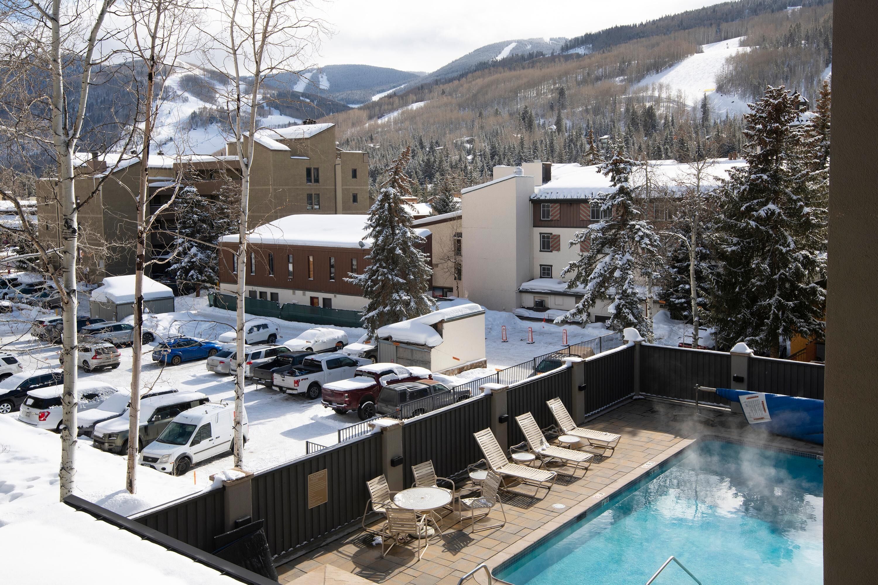 Ein Poolbereich mit Liegestühlen, einem Whirlpool und Blick auf schneebedeckte Berge.