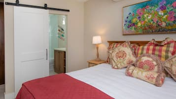 Un dormitorio con cama, mesita de noche, lámpara, un cuadro y una puerta corredera.