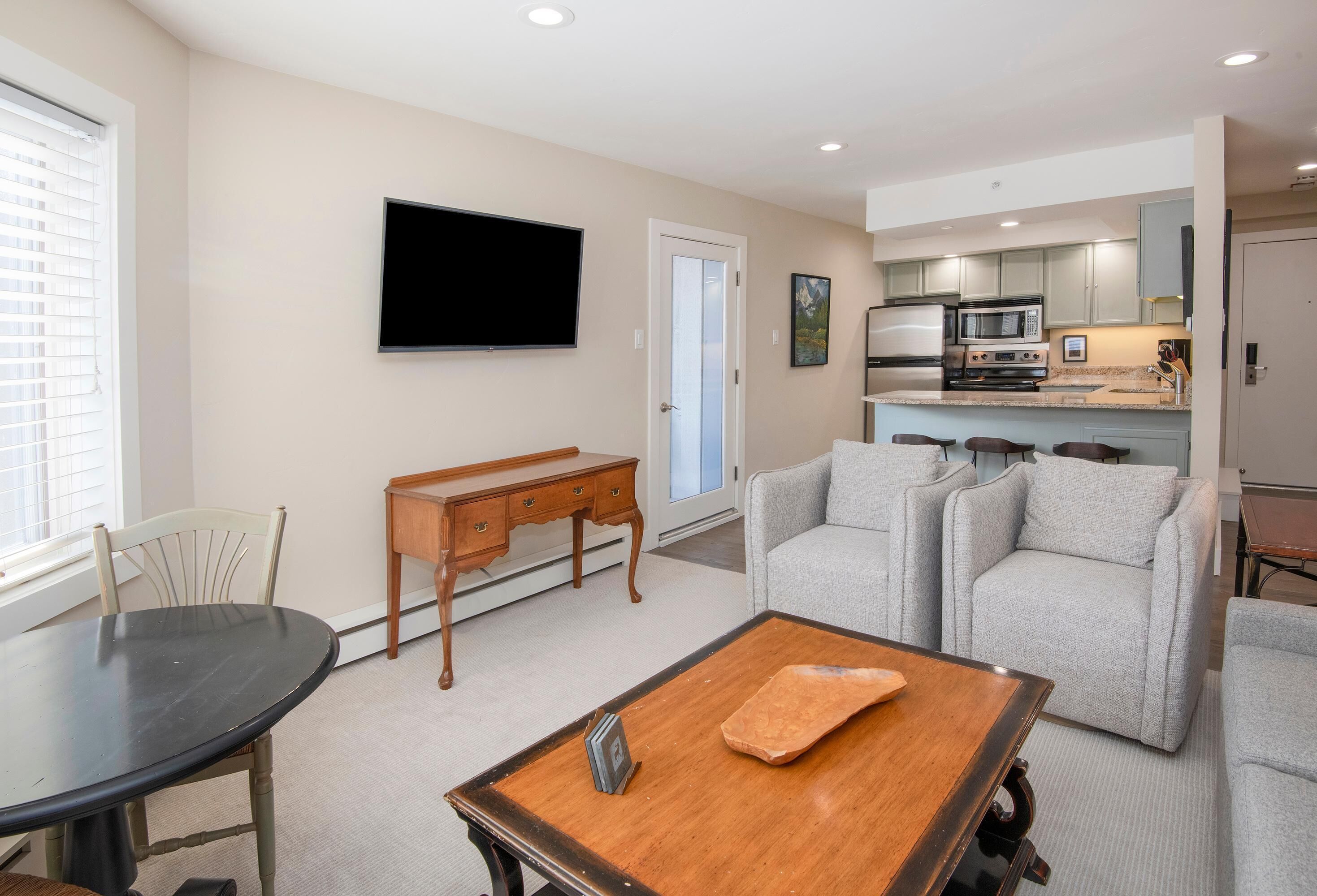 A living room with a TV, a dining table, a sofa, and a kitchen area with appliances.