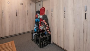 A locker room with numbered lockers, a bench, and a snowboard leaning against the wall. - Westwind 203 1BD Platinum Condo in Lionshead Village With A/C (Vail)