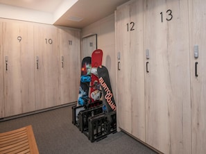Spogliatoio con armadietti numerati, una panca e una snowboard appoggiata al muro.