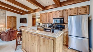 A kitchen with wooden cabinets, a stainless steel refrigerator, and a built-in island. - Treetops 5C, 3BD Ski-in Ski-out Condo (Vail)