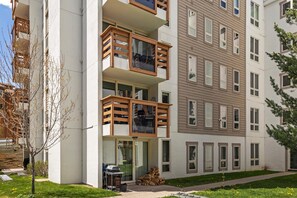 A multi-story residential building with balconies, a covered entrance, and a small outdoor seating area. - Treetops 5C, 3BD Ski-in Ski-out Condo (Vail)