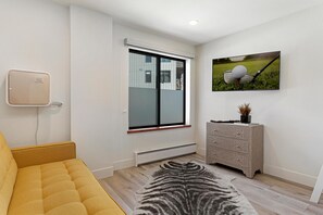 Ein modernes Wohnzimmer mit einer Couch, einem Zebra-Teppich, einem an der Wand montierten Fernseher und einem dekorativen Schrank.