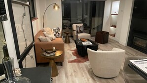 Ein modernes Wohnzimmer mit einer Couch, Sesseln, einem Couchtisch und einem Kamin.