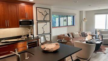 Una cocina moderna con armarios de madera, un lavamanos de acero inoxidable y un comedor con mesa y sillas.