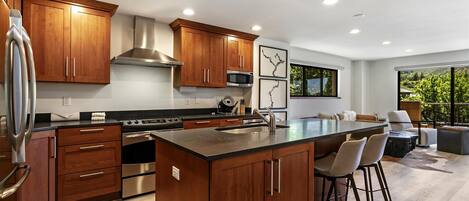 A modern kitchen with wooden cabinets, stainless steel appliances, and a large island with bar stools.
