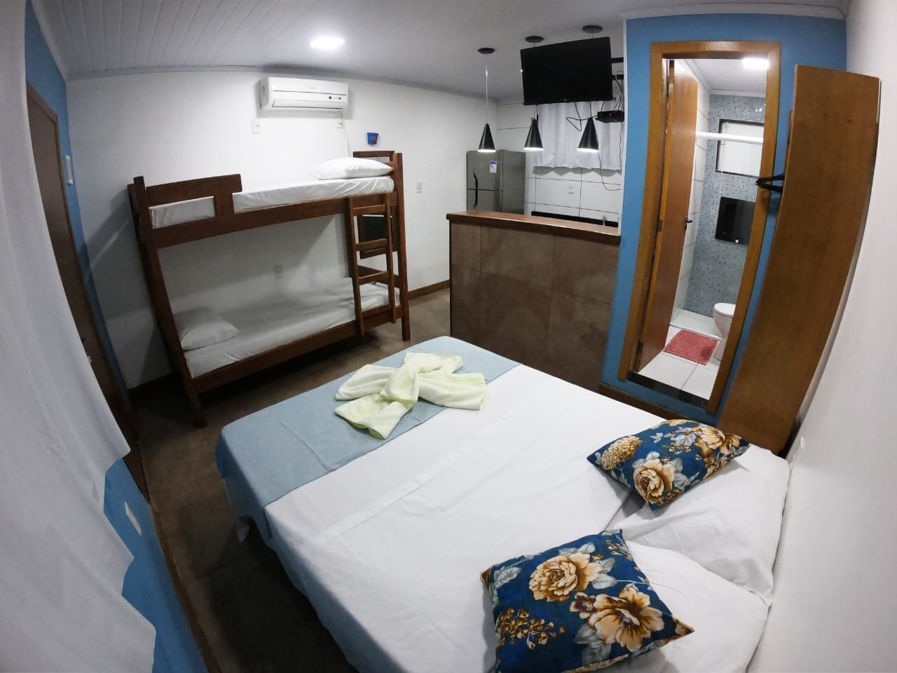 A bedroom with bunk beds, a desk, a mirror, and a television.
