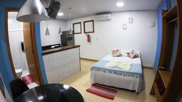 Una habitación con cama, escritorio, silla, mesa y lámpara colgante.