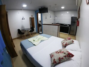 A room with a bed, a desk, a chair, a kitchenette, and a TV. - Casa da Ilha (Angra dos Reis)