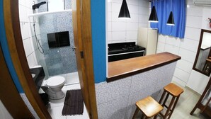 Una cocina compacta con encimera, taburetes y un lavabo.