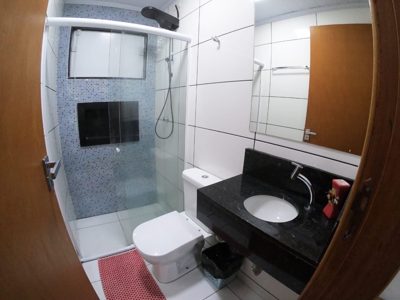 A bathroom with a shower, toilet, sink, and a mirror.