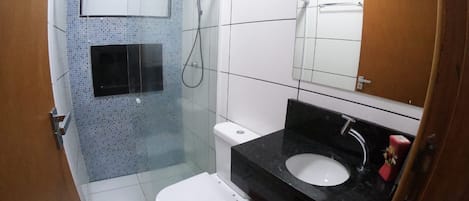 A bathroom with a shower, toilet, sink, and a mirror.