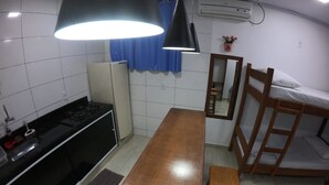 Cocina compacta con estufa, lavamanos y una mesa de comedor de madera.