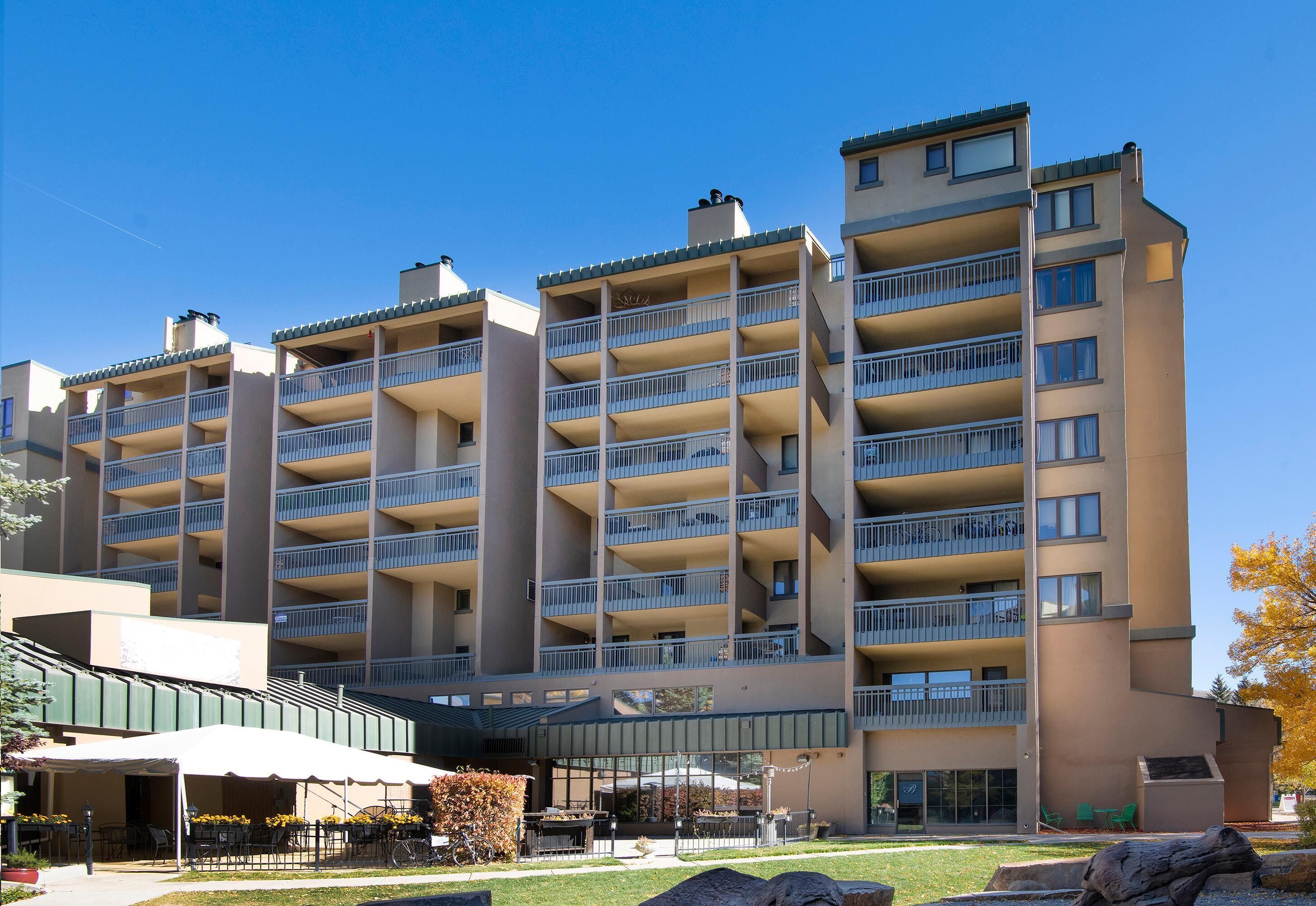 Um hotel com vários andares, varandas, área de estar ao ar livre e um pátio coberto.