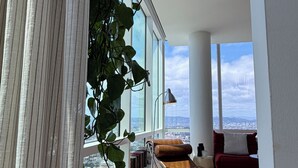 Moderni olohuone, jossa on suuri ikkuna, nahkasohva, pieni pöytä ja papupussi-tuoli.