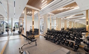 Ein Fitnessraum mit Spiegelwänden, Krafttrainingsgeräten und verschiedenen Kurzhanteln.