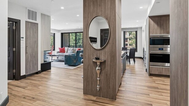 Un interior moderno con una columna central, un espejo redondo y una cocina con hornos integrados.