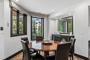 A dining area with a round table, black chairs, and a view of greenery outside. - Luxury Ski condo W/Resort Amenities | Walk to lift (Beaver Creek)