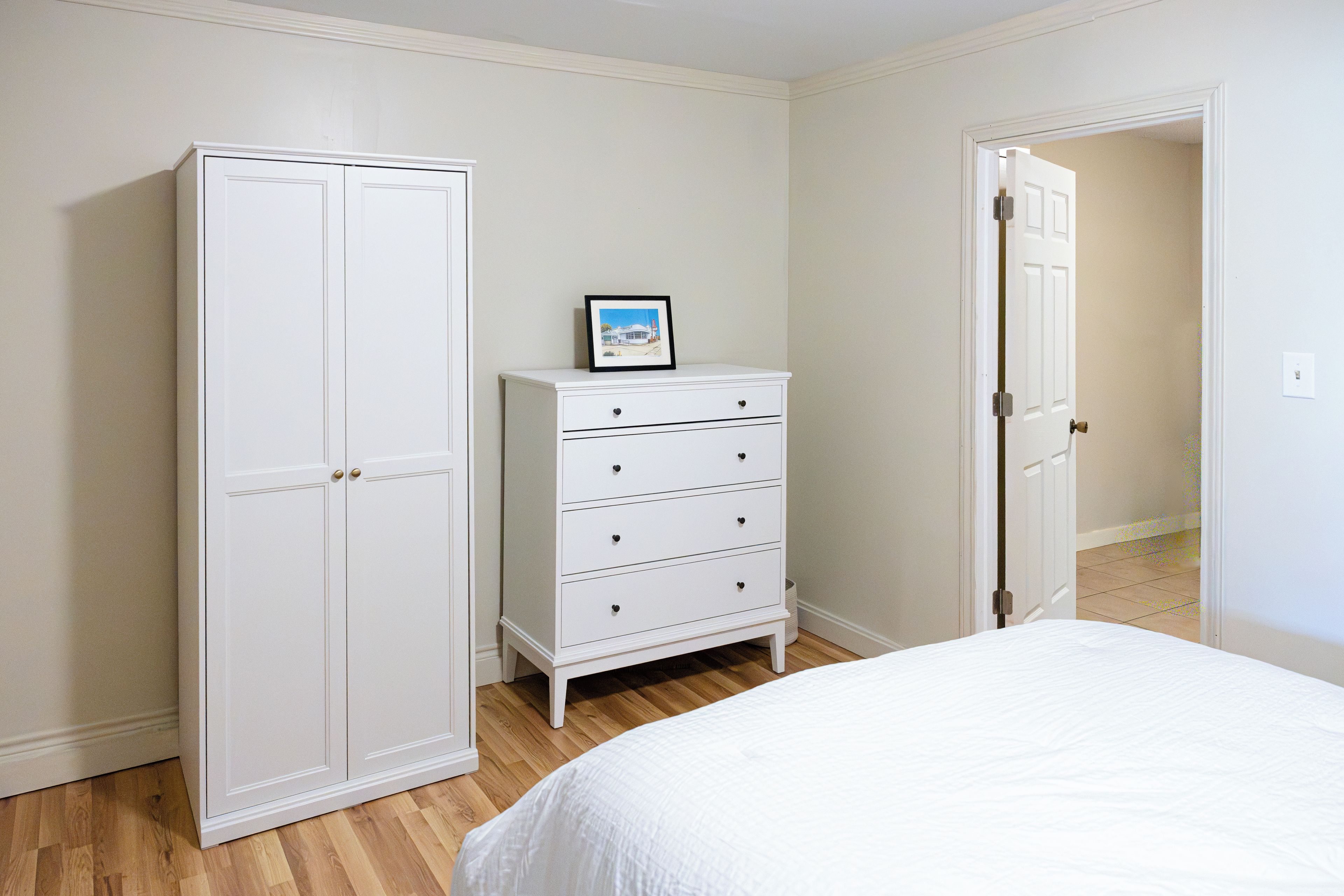 A bedroom with a bed, a dresser, and a wardrobe.