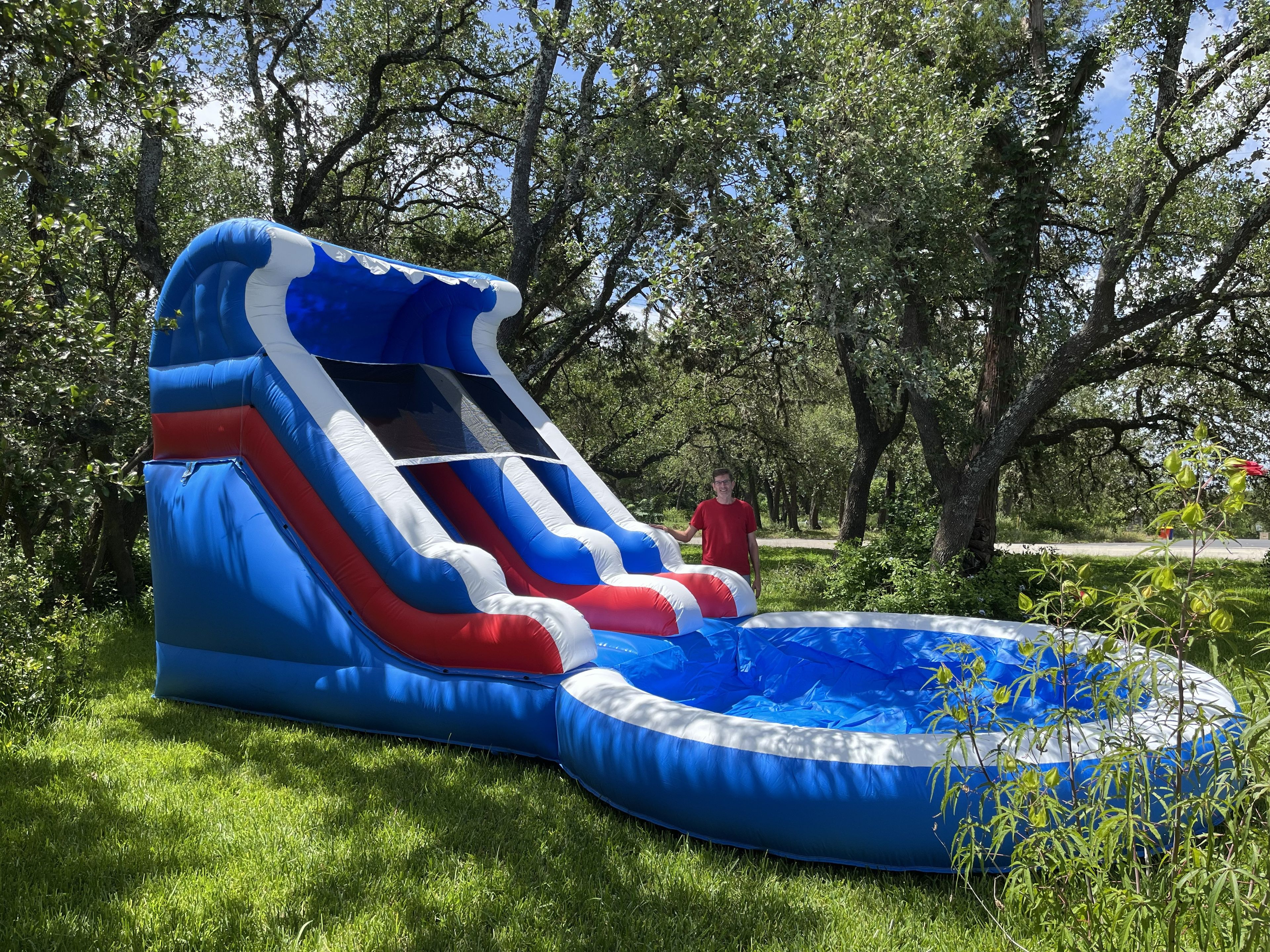 An inflatable slide in a grassy area with trees in the background.