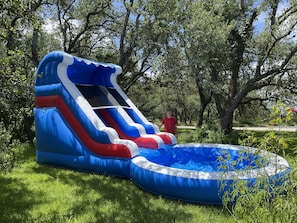 An inflatable slide in a grassy area with trees in the background.