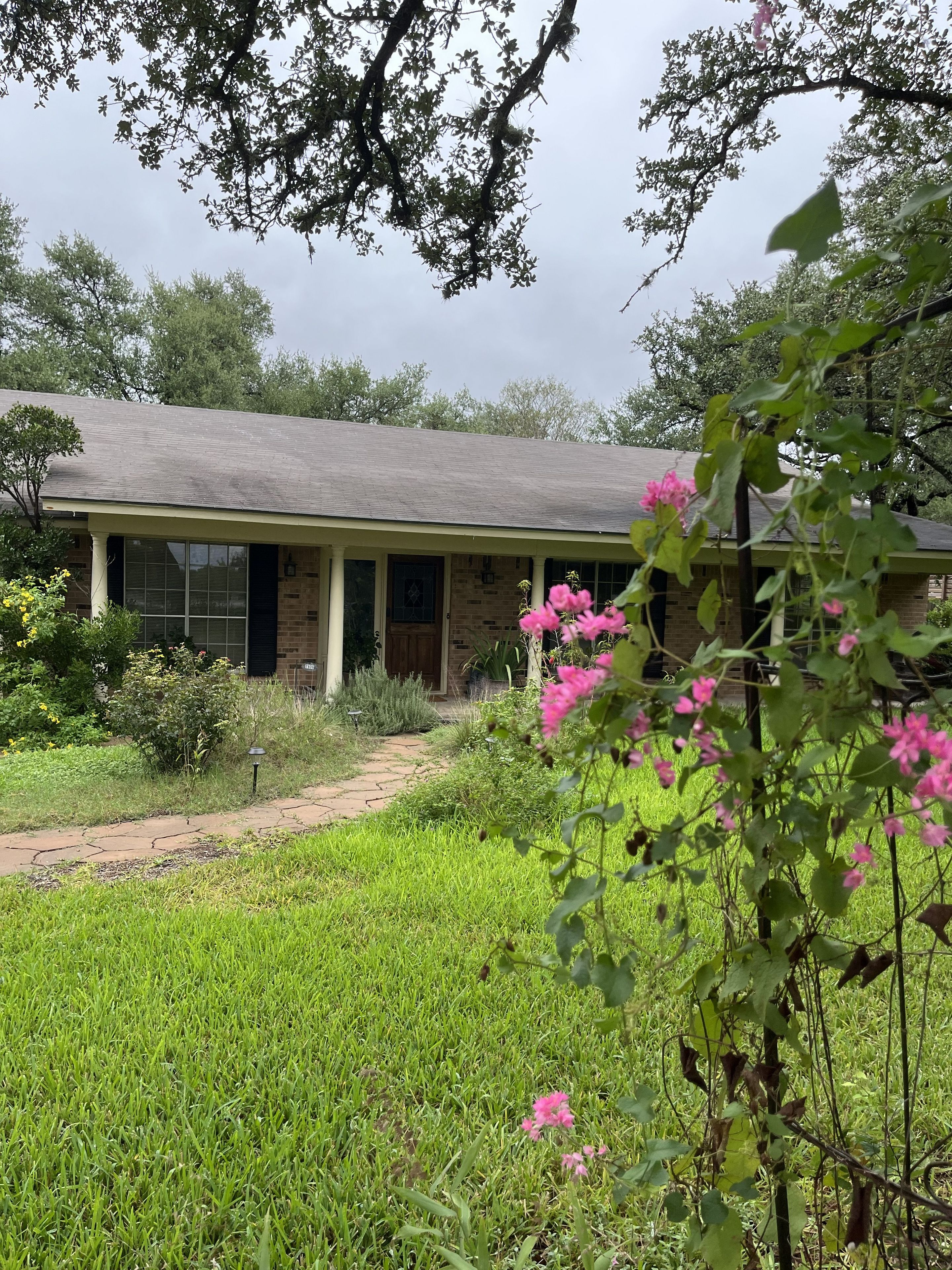 A house with a brick exterior, a front porch, and a pathway leading to the entrance.