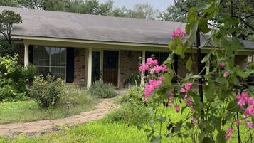 A house with a brick exterior, a front porch, and a pathway leading to the entrance.