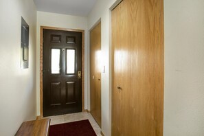 A hallway with a dark wooden door, a wooden bench, and a red rug. - Snow Fox 201, 2BD Modern Vail Condo (Vail)