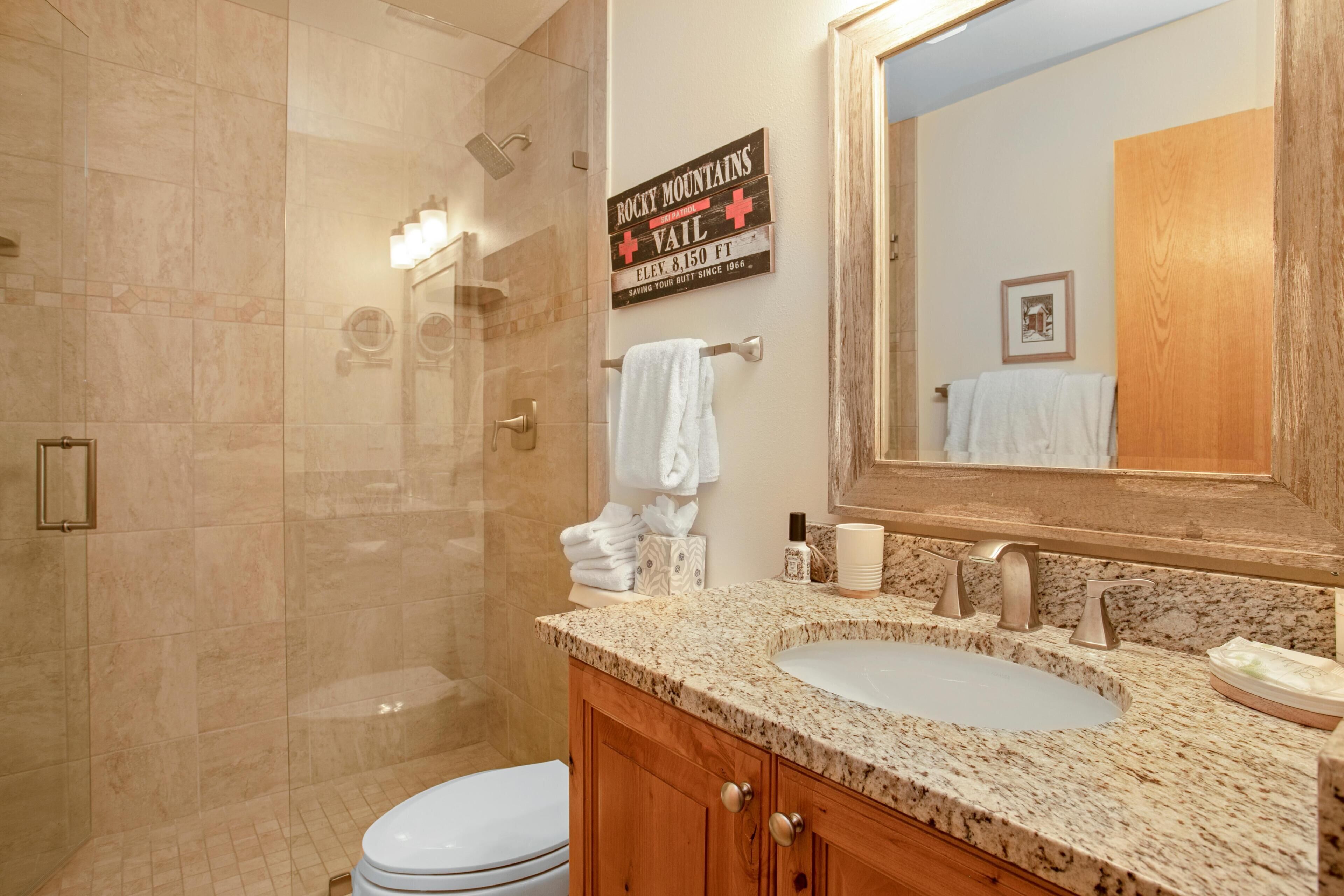 A bathroom with a shower, a sink, and a vanity with a mirror.