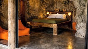 A rustic bedroom with a wooden bed, stone walls, and a stone floor. - Cozy Cave - With a View (Lancaster)