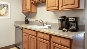 A kitchen with wooden cabinets, a dishwasher, a coffee maker, and a sink. - Treetops Plaza One, 2BD Ski-in Ski-out Condo (Vail)