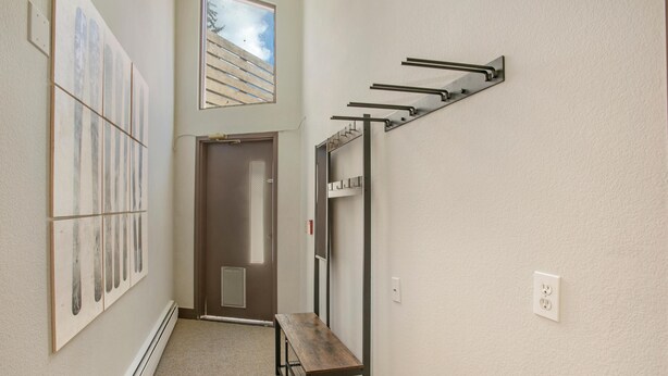 A hallway with a bench, a coat rack, and a door leading to another room. - Treetops Plaza One, 2BD Ski-in Ski-out Condo (Vail)