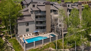 Un hôtel à plusieurs étages doté d’une piscine, d’un espace extérieur aménagé et offrant une vue sur les collines environnantes.