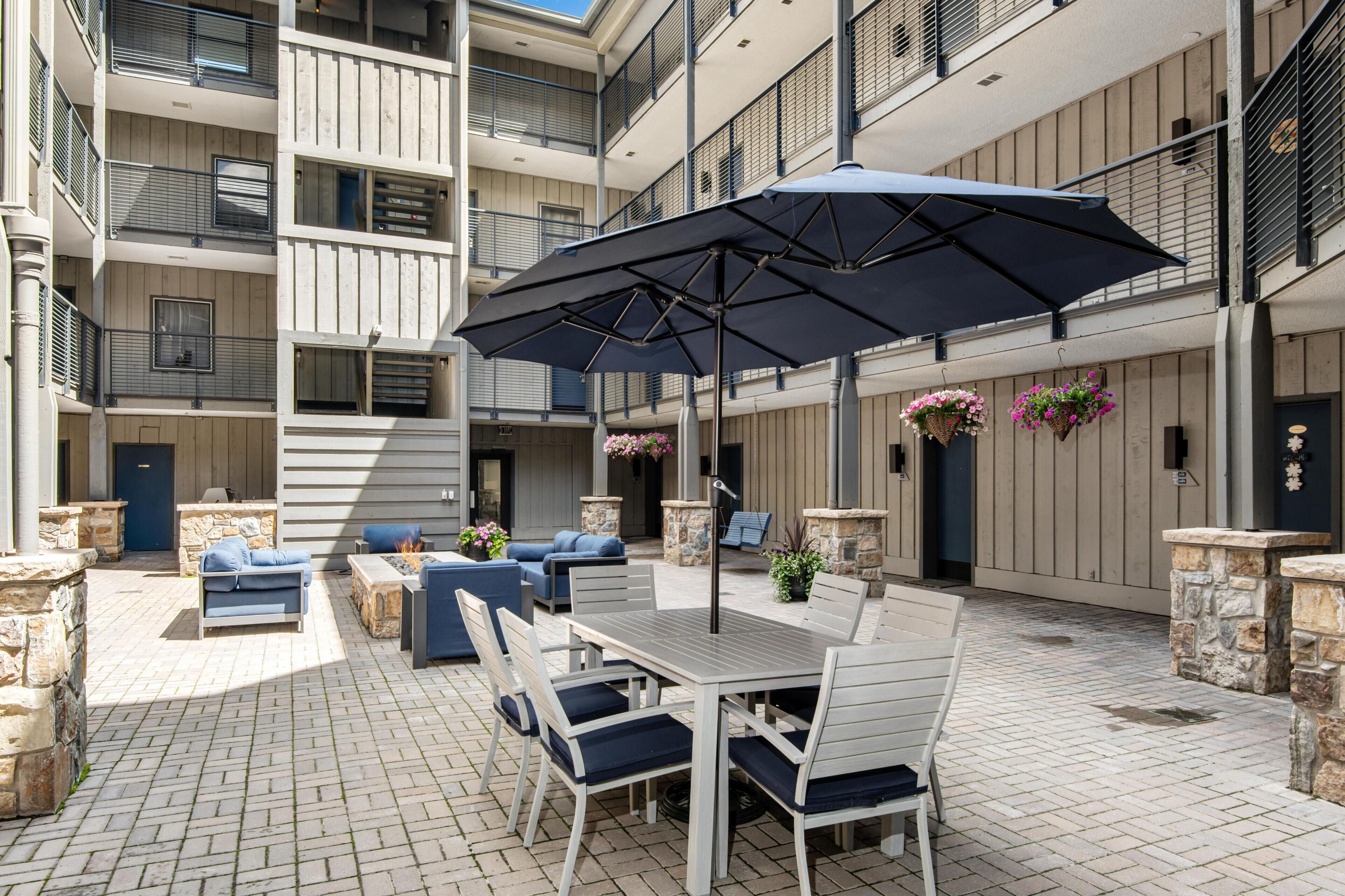 Eine mehrstufige Außenpatio mit Esstisch, Stühlen und Sonnenschirm.